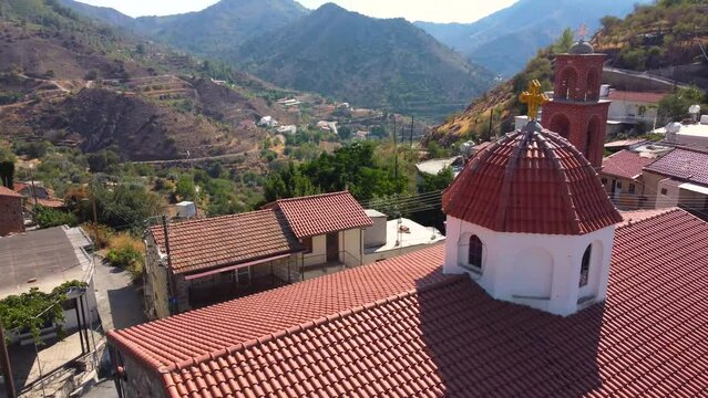 Aerial drone footage of traditional countryside hilltop village Farmakas, Nicosia, Cyprus. Close up establish scene of christian church Saint Irene with ceramic tiled roof dome from above