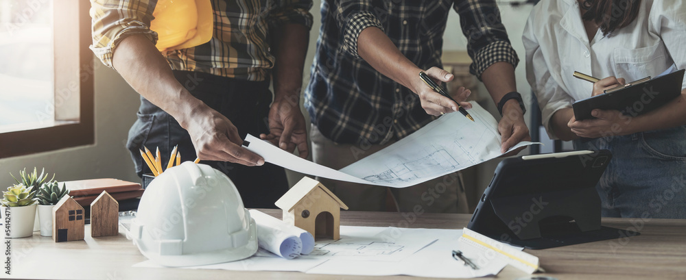 Wall mural team construction engineers working at construction site with blueprint on table