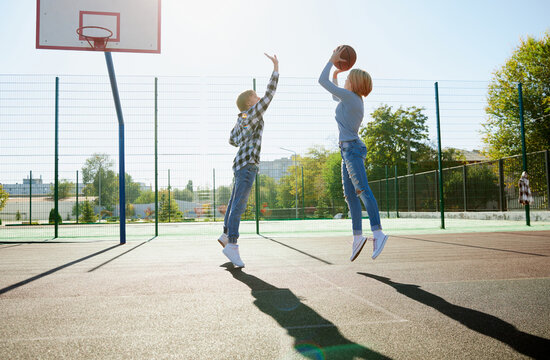 Group of teens, students playing street basketball at basketball court outdoors. Sport, leisure activities, hobbies, team, friendship