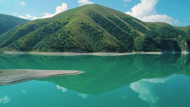 Aerial over lake Kezenoy-am with turquoise water and tall mountains around. Stunning scenery in highlands of Chechen Republic, Russia