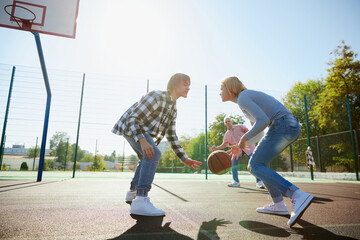 Group of friends bonding outdoors to play street basketball. Teens wearing casual style clothes. Kids look happy, delighted. Sport, energy, motion