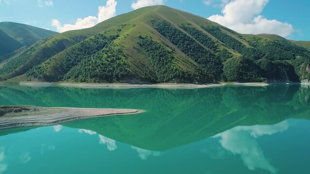 Aerial over lake Kezenoy-am with turquoise water and tall mountains around. Stunning scenery in highlands of Chechen Republic, Russia