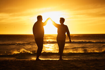 Fototapeta premium Love, ocean and sunset, silhouette of couple on beach holding hands in Bali. Waves, romance and man and woman dancing in evening sun on romantic vacation spending time together in nature and sea sand
