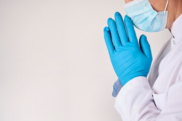 Praying doctor hands in blue rubber gloves