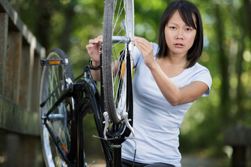 woman is fixing the electric bicycle in the park