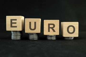 Euro currency weakening, value depreciation and devaluation concept. Decreasing stack of coins on dark black background.