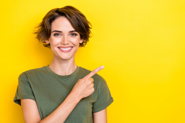Photo of satisfied optimistic nice girl with bob hairstyle wear khaki t-shirt indicating empty space isolated on yellow color background