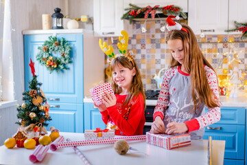 process of packing Christmas gifts, girls 7 years old and 10 years old in christmas pajamas use jute thread to tie gift