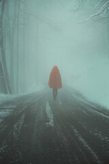 Figure with red cloak on a misty winter road