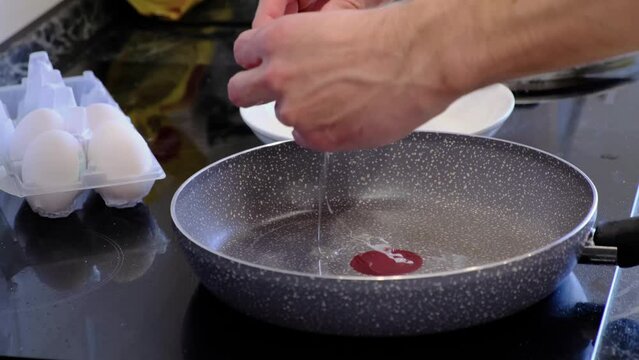 man cooks fried eggs in a teflon pan, pour refined palm oil into the pan. Cooking process of tasty healthy food.
