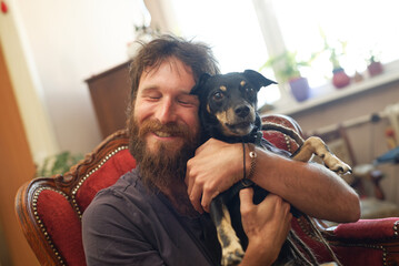 Cute love between a man and a dog; rastafarian dreadlocks man holding his dog, petting and hugging...