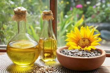 Rolgordijnen Bottles of sunflower oil, seeds and flower on wooden table indoors © New Africa