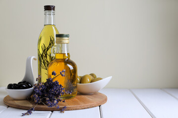 Different cooking oils and ingredients on white wooden table against light background, space for...