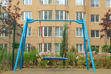 Fototapeta na wymiar Light blue nest swing on outdoor playground in residential area