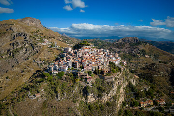 Fototapeta na wymiar Aerial view of the mountains and a small village on top of Castelmola. Sunny morning. Sicily. Italy