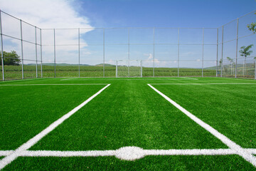 Artificial green soccer field with white line marking on a sunny summer day © raresb