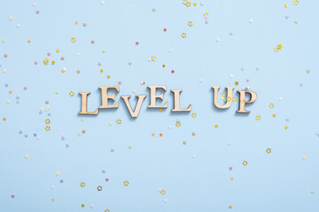 Level up wooden inscription on a colored background with stars. Achievement concept