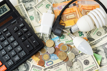 Calculator, euro and dollar banknotes, coins. Tax time, bill payment, calculator for counting. Lamp, plug, cord, electricity. The concept of the energy crisis, price increases.
