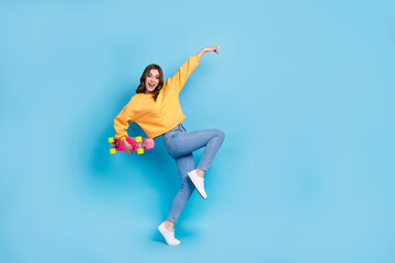 Fototapeta na wymiar Full length photo of funny adorable girl dressed yellow pullover holding skateboard having fun isolated blue color background