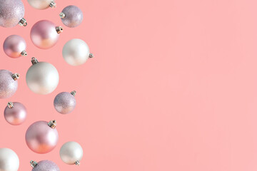 Creative arrangement made of baubles falling against.pastel pink background. Minimal New Year layout with copy space. Christmas card concept. Holiday aesthetic.