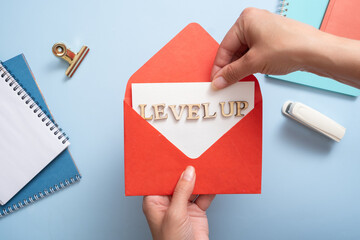 Level up inscription in the red envelope in female hands. Business and achievement concept