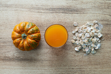Orange pumpkin, pumpkin seeds and a glass of pumpkin juice on a wooden background, pumpkin is a source of vitamins and antioxidants