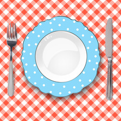Blue plate with figured edges and polka dot pattern placed on orange check classic seamless tablecloth. Closeup view from above.