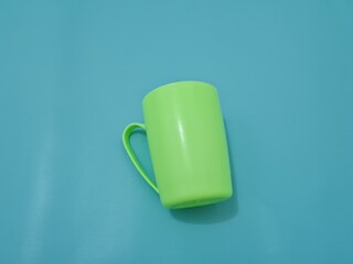 A glass made of plastic with a green handle