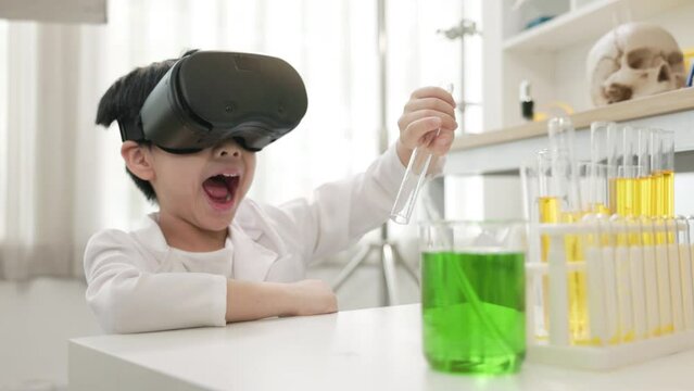 asian boy using VR goggles technology for virtual mixing chemical liquid in school laboratory.  young scientist learning chemical class with 3d virtual education technology.  