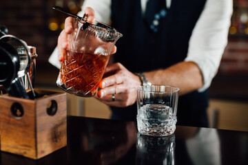 close up of barman pouring cocktail into glass