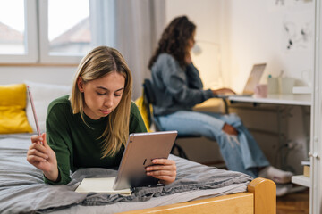 college female student using digital tablet in room