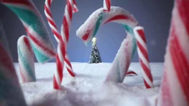 Fondo de Navidad nevando con caramelos navideños de colores, árbol de navidad y estrella luminosa de juguete.