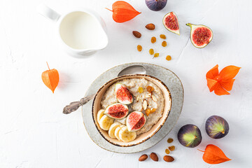 irregularly shaped ceramic bowl with organic oatmeal porridge with ripe fig wedges and almonds. top...