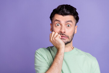 Photo of scared frightened guy with brunet hairstyle stubble wear t-shirt hold hand on chin staring...