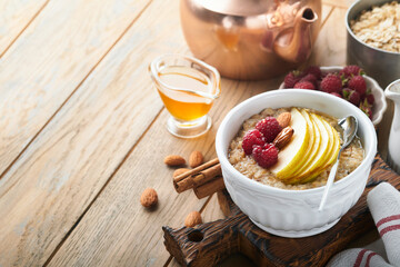 Oatmeal. Bowl of oatmeal porridge with raspberry, pear and honey on old wooden table background. Hot and healthy food for Breakfast, top view, flat lay