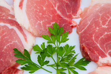 Raw Pork Slice in White Round Plate decorated with parsley. Fresh raw pork.