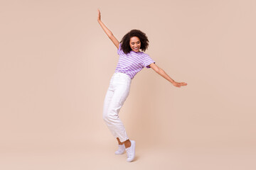 Photo of funky adorable girl dressed purple t-shirt dancing having fun isolated beige color...