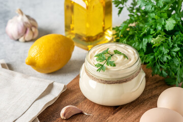 Aioli sauce with ingredients on a wooden cutting board. Side view, selective focus. Homemade...
