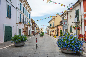 The beautiful main street of San VIto Chietino with colored flowers and facades - obrazy, fototapety, plakaty