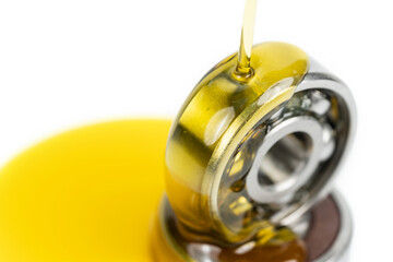 Closed up macro, Pouring automotive engine oil into ball bearing isolated on white background with copy space, engineering and industrial concept. Motor oil on bearing