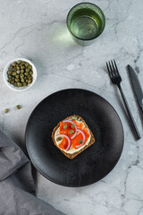 open sanwiches with dark rye bread, salmon, pickled capers, red onion,black background, top view.