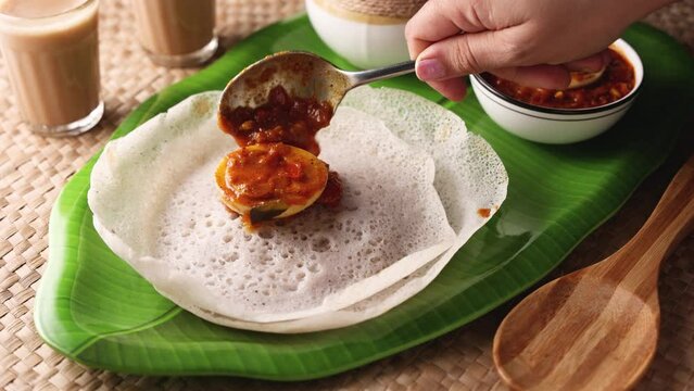 Appam rice noodles, a popular traditional steam cooked Kerala breakfast dish with hot and spicy egg roast curry on a houseboat, Alleppey, India. South Indian food. noolputtu Sri lankan