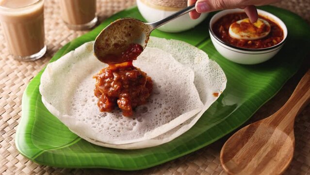 Appam rice noodles, a popular traditional steam cooked Kerala breakfast dish with hot and spicy egg roast curry on a houseboat, Alleppey, India. South Indian food. noolputtu Sri lankan