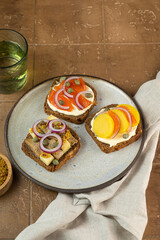 assorted toasts with dark rye bread, herrings, smoked salmon and capers on wood background
