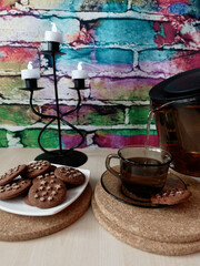 pouring tea in a cup and cookies on a table