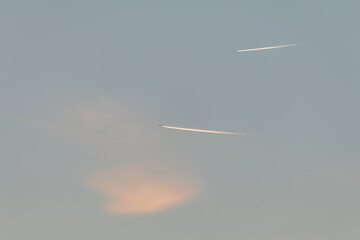 Airliners in flight in a cloudy pink and orange sky in late summer.