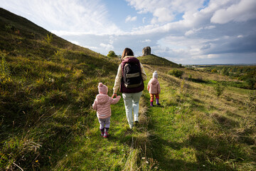 Kids exploring nature.  Mother with two daughters near big stone in hill. Pidkamin, Ukraine.