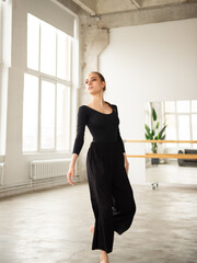 Modern female dancer in black outfit practices in a dance studio - 541452554