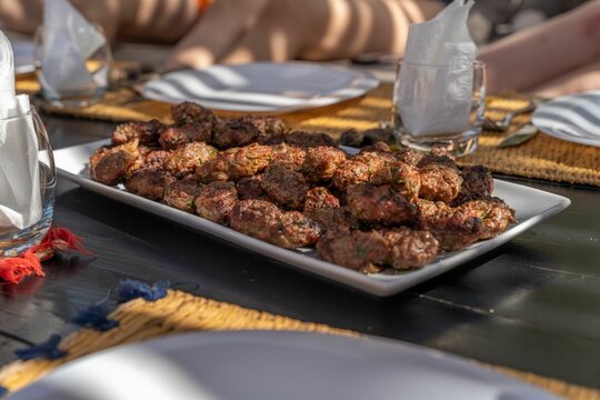 Moroccan Kefta On A Plate With A Dinner Scene In The Background