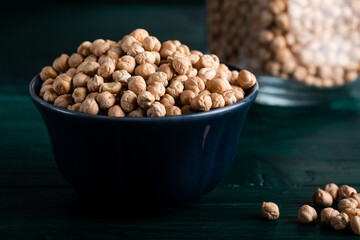 Dried chickpeas in a wooden bowl on a wooden background.